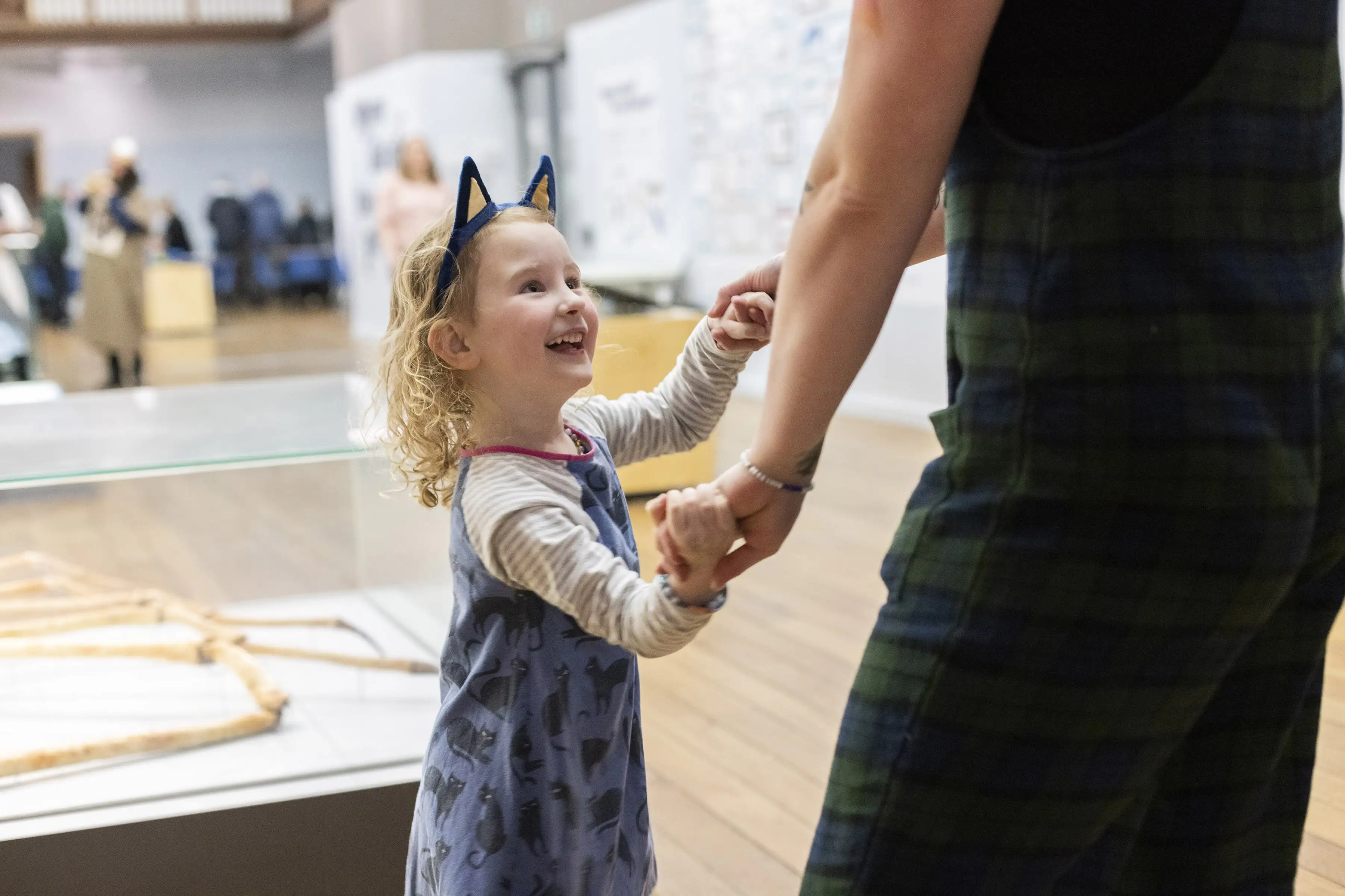Girl with cat ears headband in a gallery holding hands with an adult